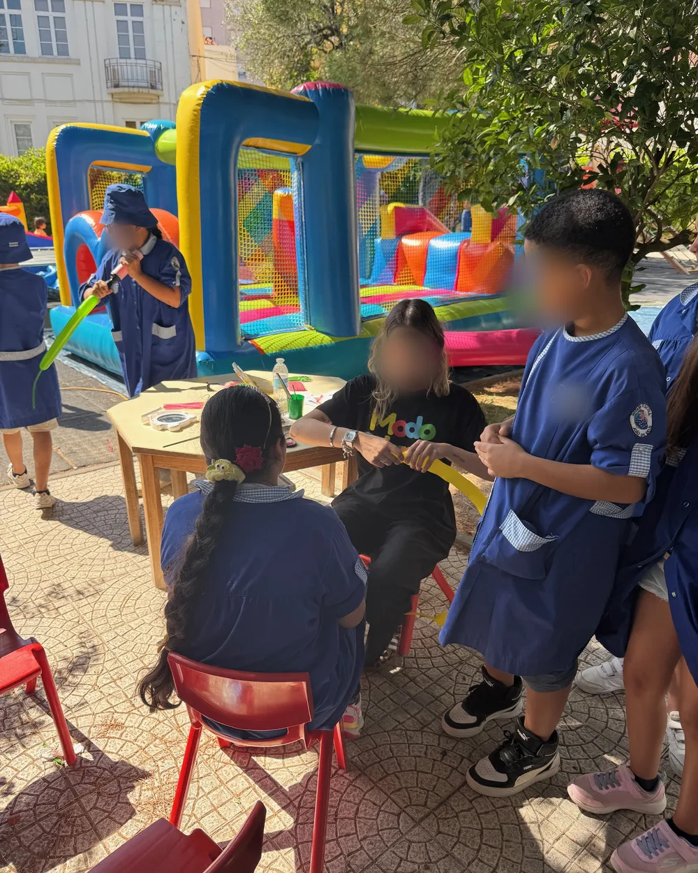 Crianças de escola básica a receber balões modelados junto ao insuflável