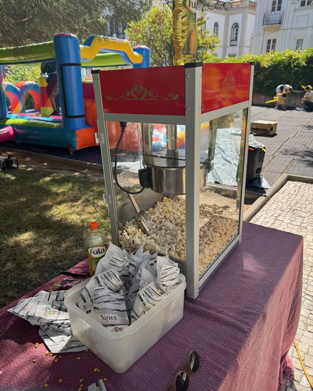 Máquina de pipocas montada num evento de escola com insuflável ao fundo